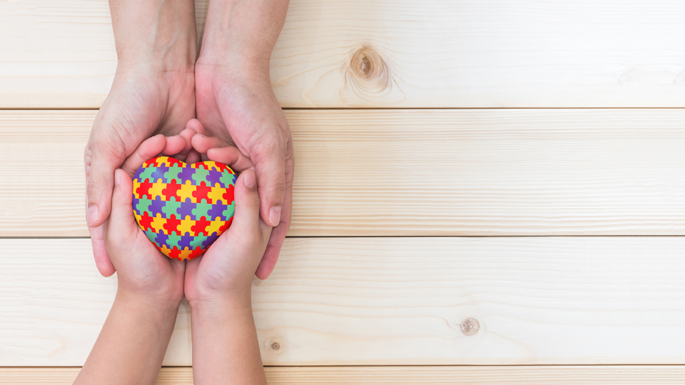 Two hands holding heart with puzzle pieces