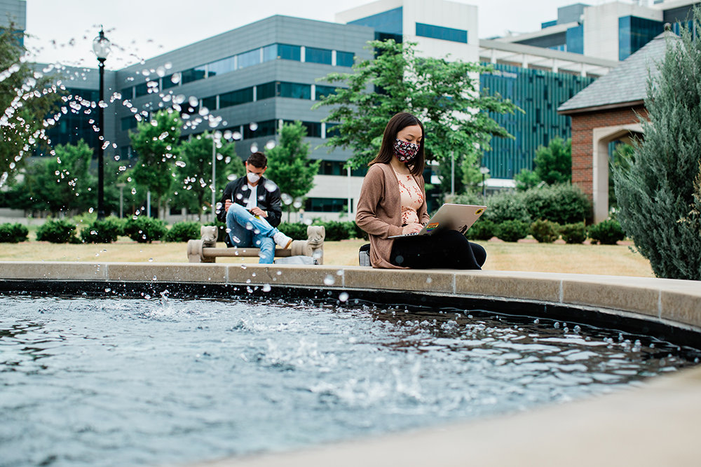 woman and man sitting at fountain with mask on