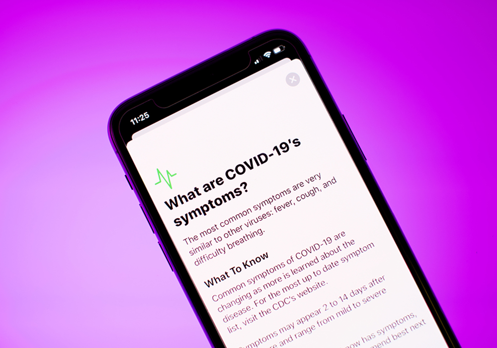 Phone with article titled "What are COVID-19's symptoms" directing people to the CDC's site