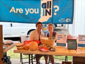 sylk and gina sitting at the all in for health desk